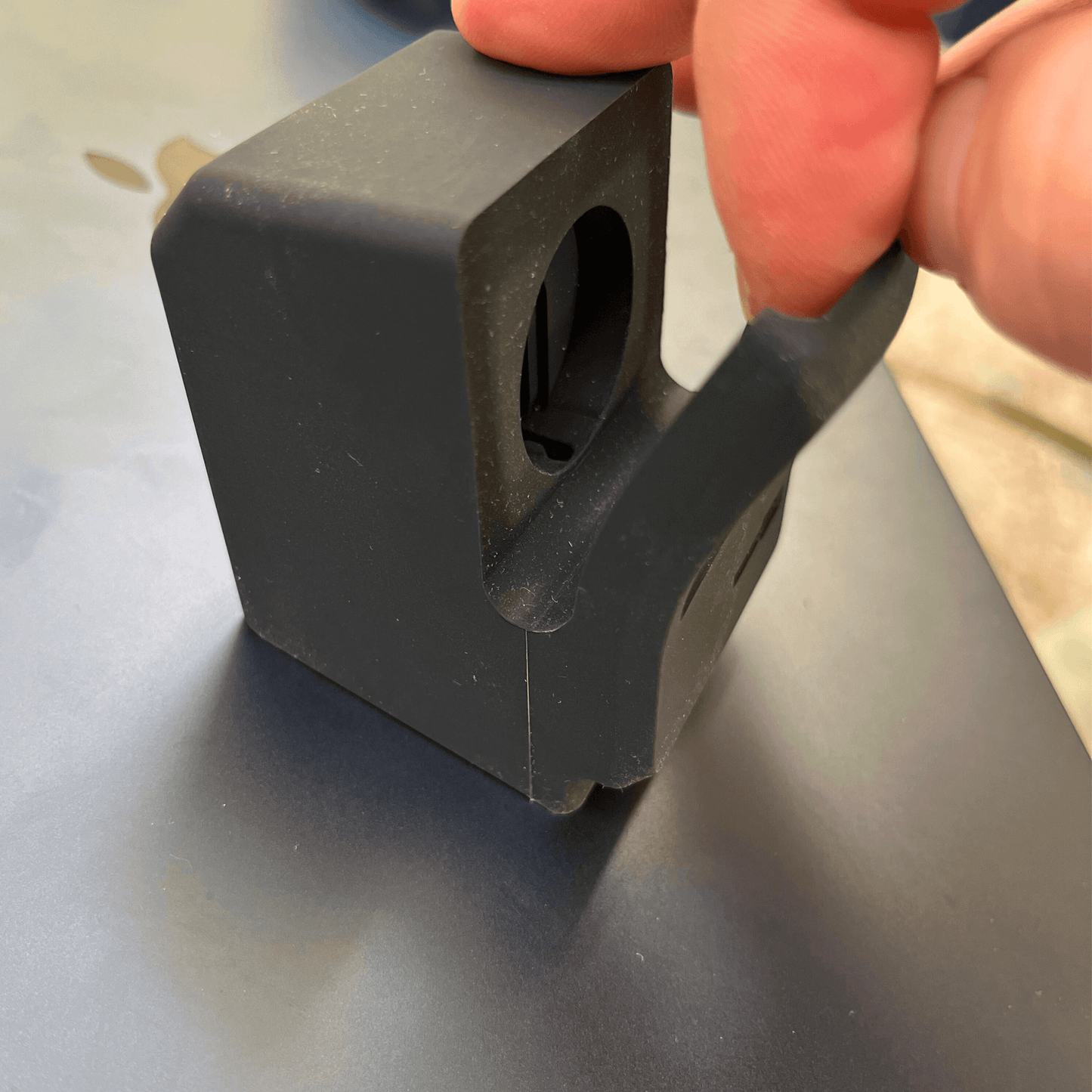 Close-up of a hand holding a black rubberized silicone cradle for a smartwatch, showcasing its design.