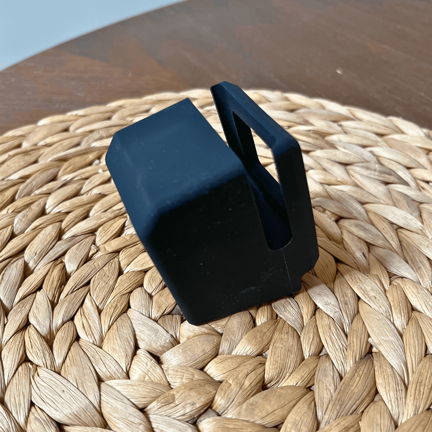 Black silicone cradle for iWatch, designed to resemble a retro computer, placed on a woven surface.