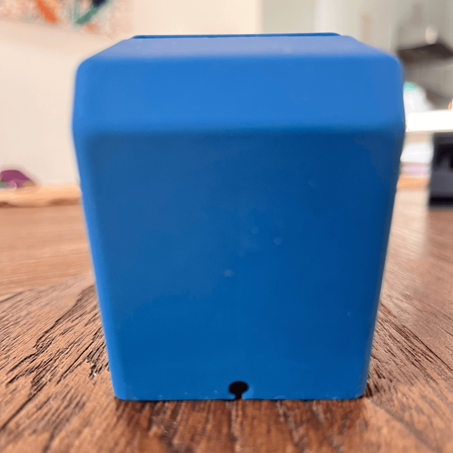 Front view of a blue rubberized silicone stand designed for Apple Watches, resembling an old computer.