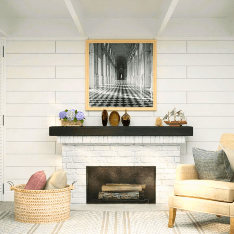 Stylish living room with a black mantel, decorative items, and a vintage framed photo above the fireplace.