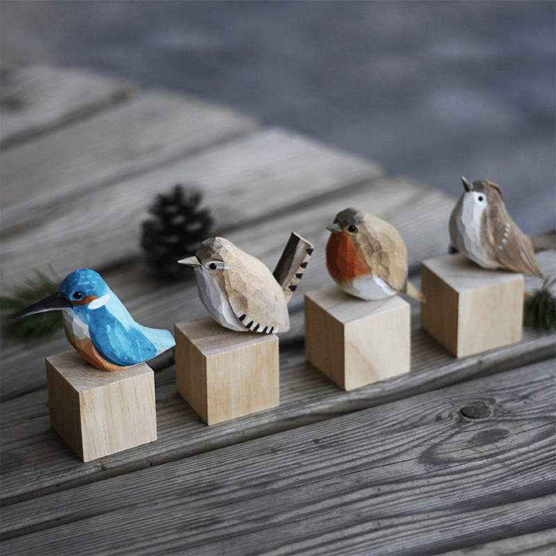 Hand-carved wooden bird ornaments displayed on wooden blocks, showcasing natural craftsmanship and intricate designs.