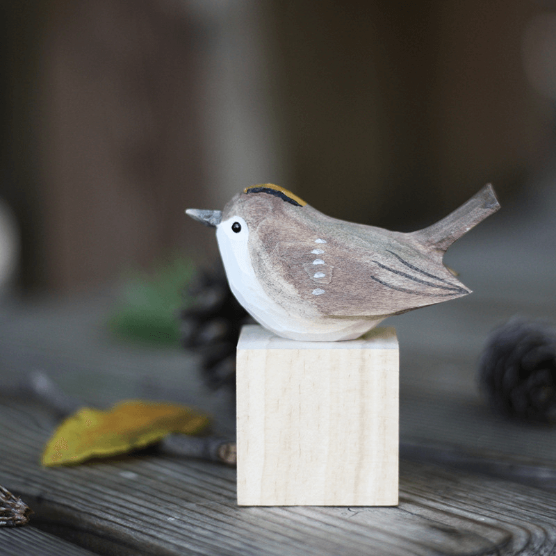 Hand carved wooden bird ornament perched on a block, showcasing detailed craftsmanship and natural colors.