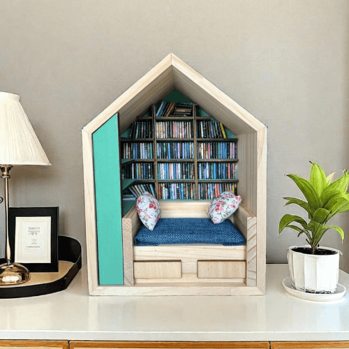 Image of a house-shaped Anxiety Book Room miniature bookshelf with tiny shelves and a cozy seating area.