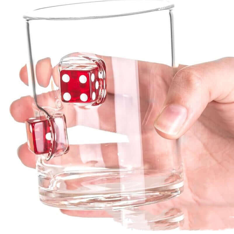 Hand holding a clear glass cup with red casino dice embedded, perfect for whiskey lovers.
