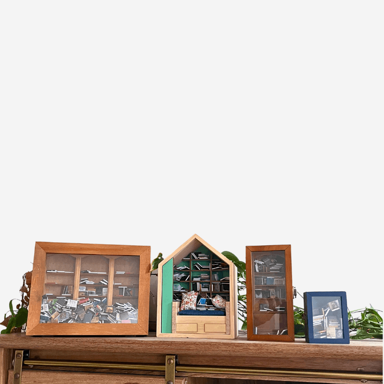 Miniature bookshelves displayed on a wooden shelf, part of the Four Piece Anxiety Bookshelf Collection.