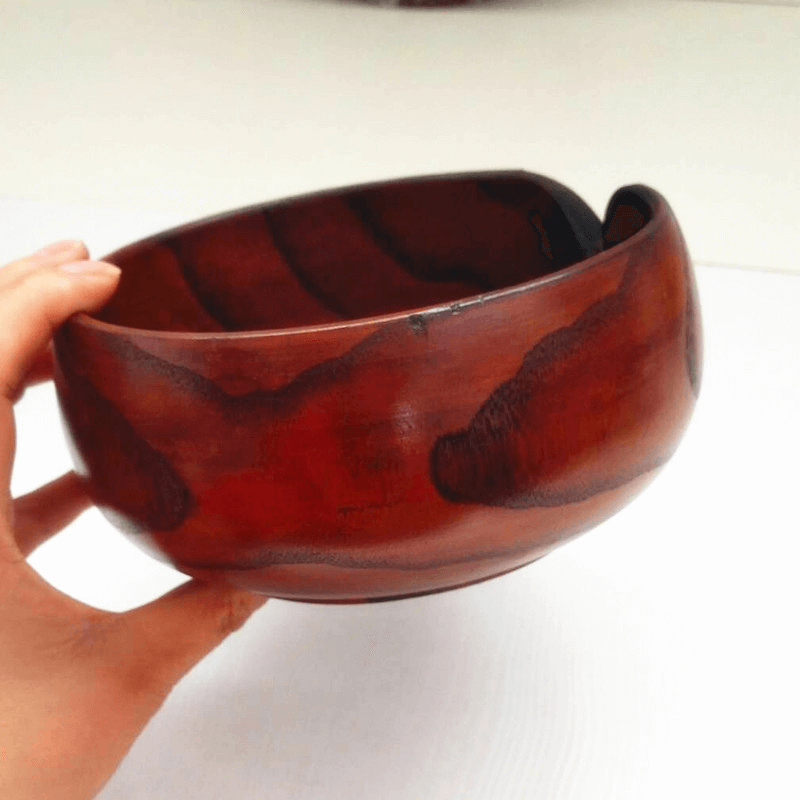 Handmade wooden crochet yarn bowl held in a hand, showcasing its unique grain and smooth finish.