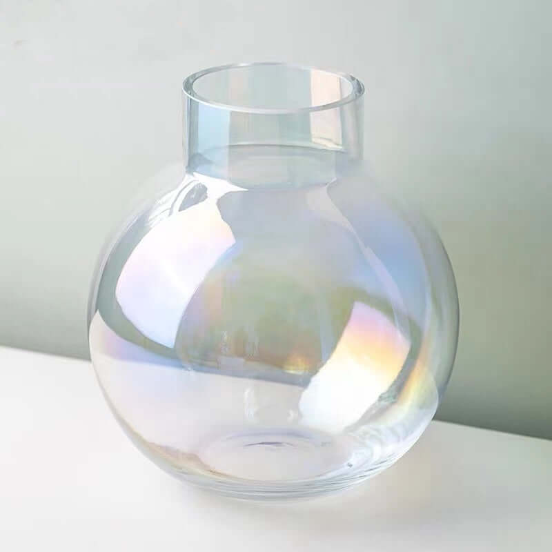 Iridescent clear glass sphere vase displaying soft rainbow reflections in natural light.