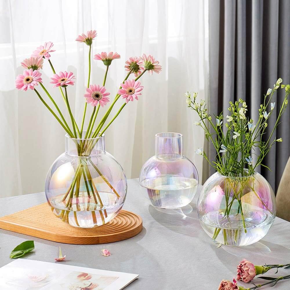 Iridescent glass sphere vases with flowers on a table, showcasing color shifting effects and elegant design.
