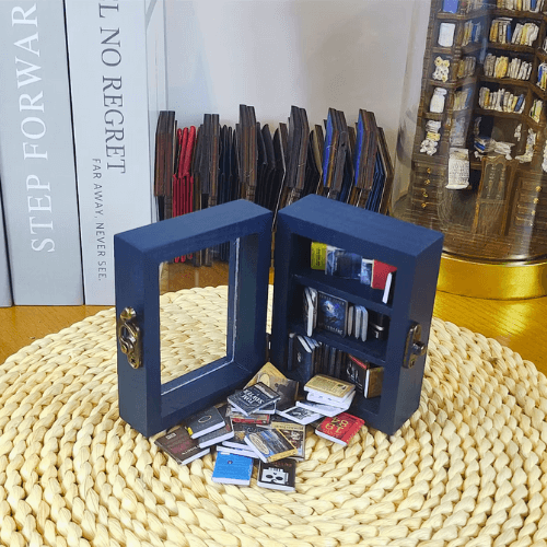 The Pocket Anxiety Bookshelf mini bookcase sits open with miniature books pouring out.