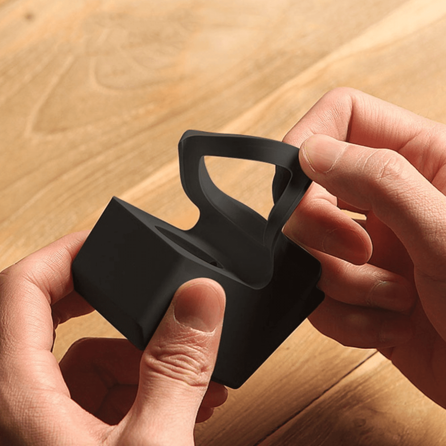 Hands holding a black silicone retro watch display cradle designed like an old computer.