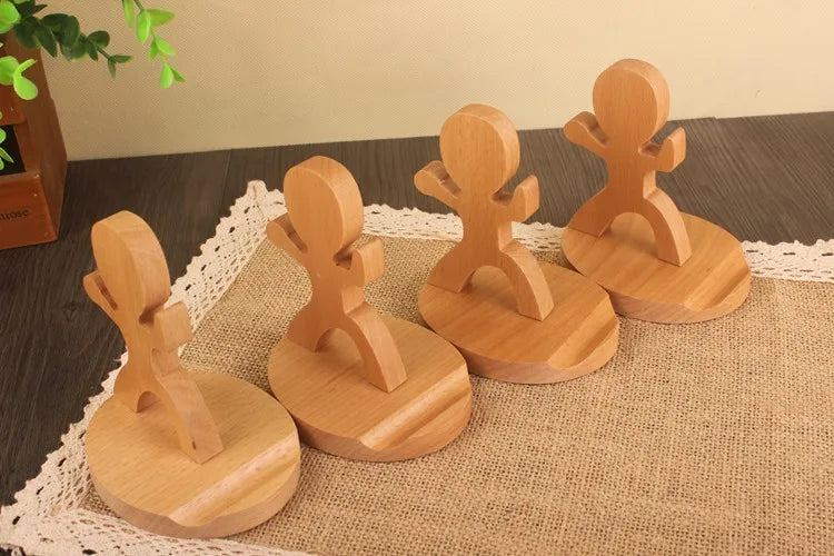 Small handmade wooden men figures that are stands for a phone.