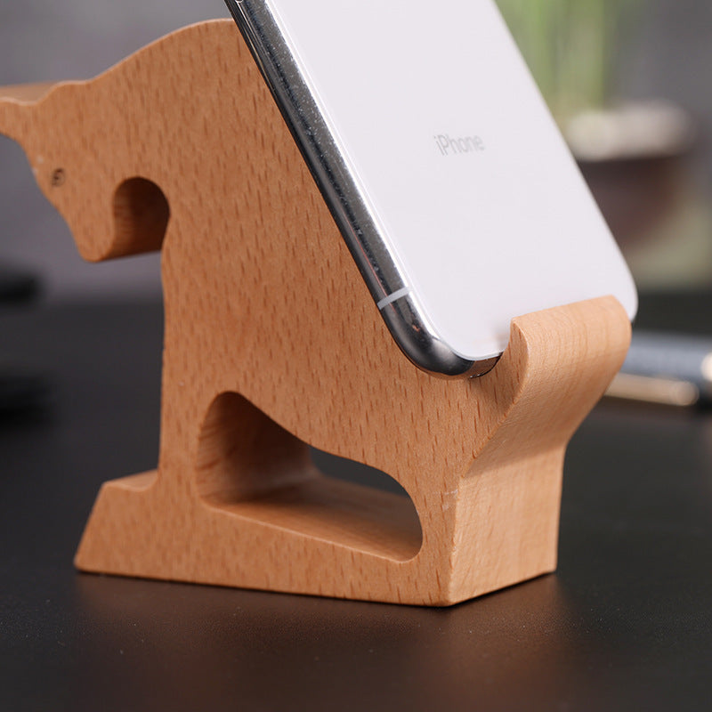 A carved wooden horse that is shaped to hold a cell phone.