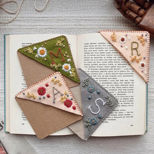 Four seasonal personalized book corners featuring a letter initial hand sewn. Available in winter, fall, spring, and summer color schemes.