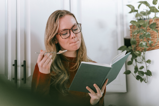 A book lover eats while reading her book.