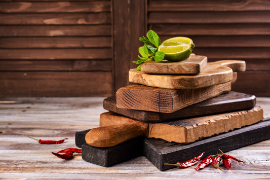 Distressed wood boards and cutting boards are displayed in rustic setting with wood panel backdrop.