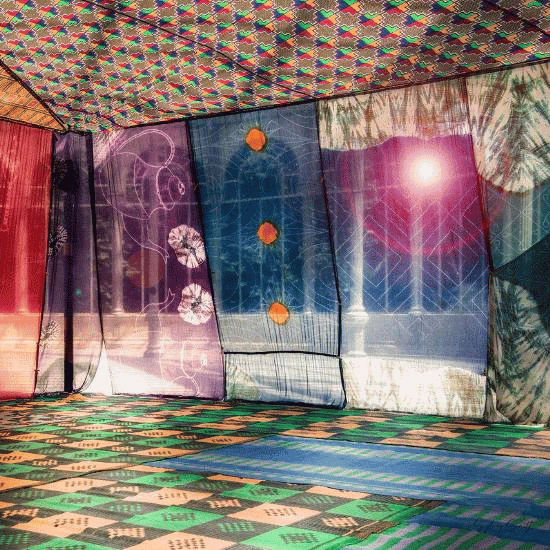 the sun shines through several hanging fabric tapestries