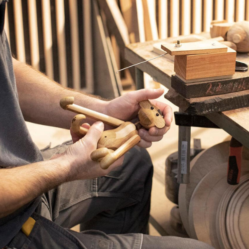 Handmade wood monkey is held by an artist.