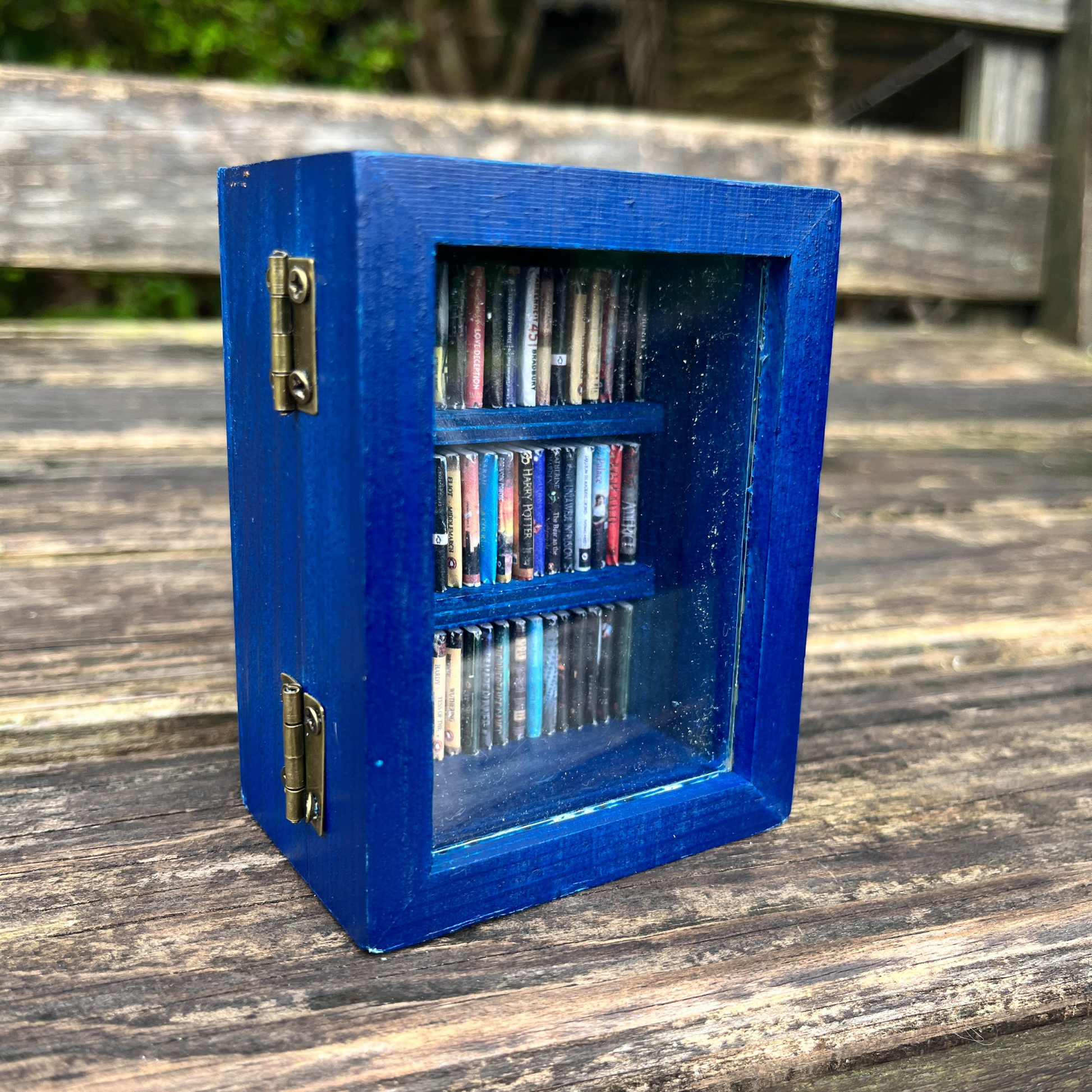 The pocket Anxiety Bookshelf sits closed on a wood bench, the books are organized with spines facing out