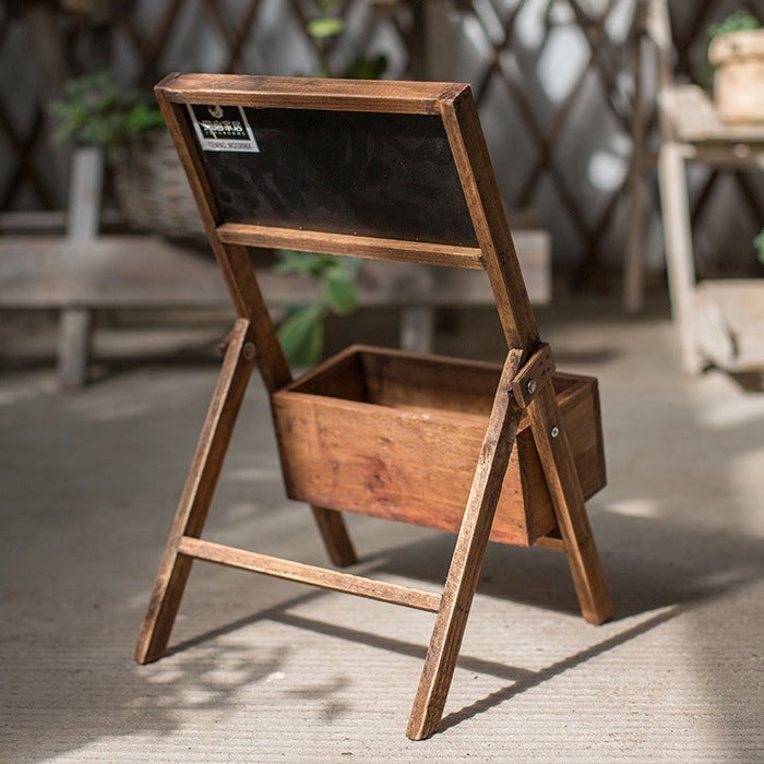 A wooden folding shelf with attached planter and chalkboard to label the plants inside.