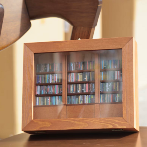 A full Anxiety Bookshelf sits on a chair. Displaying the mini real replica book spines inside the bookcase.