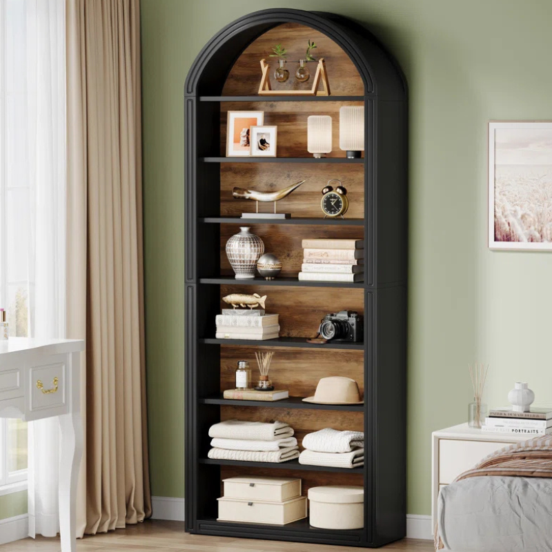 A tall and narrow black arched top bookshelf with wood grain backing. An open faced unique bookshelf for tight spaces.