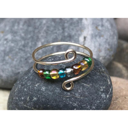 Close up image of a rainbow beaded anxiety ring for fidget, adjustable size.