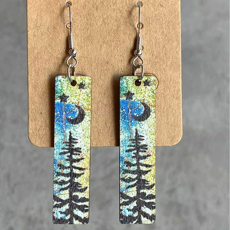 Wood mini bookmark earrings with black moon, star and pine tree silhouettes over a watercolour background.