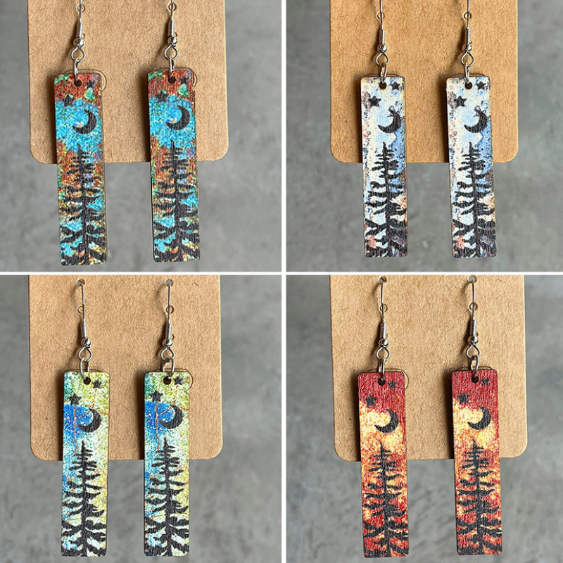 Wood mini bookmark earrings with black moon, star and pine tree silhouettes over a watercolour background.