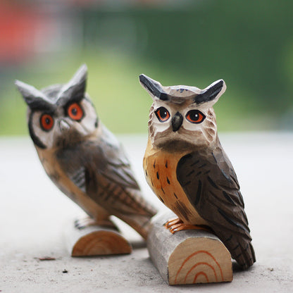 Two hand carved long eared owl ornament sits perched on a small wood log.