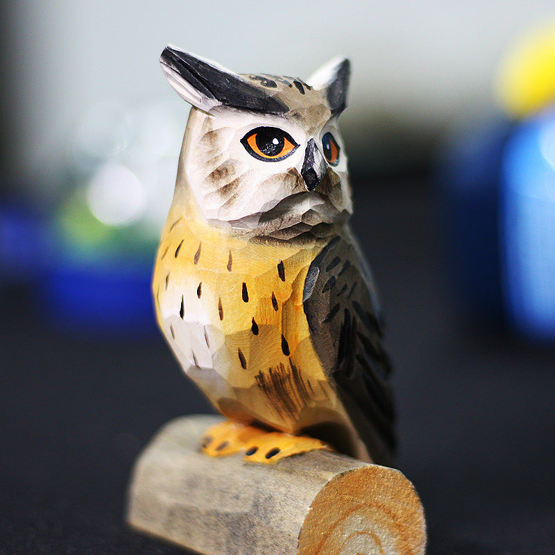 Hand carved northern white faced owl ornament sits perched on a small wood log.