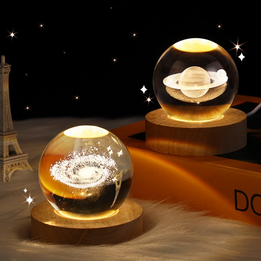 Two illuminated three dimensional galaxy engraved crystal balls sit on their LED lit wooden base.