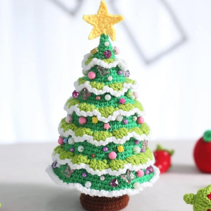 The small sized handmade crochet christmas tree plushie is displayed beside an apple crochet plushie.