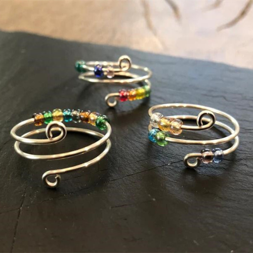 Three rainbow beaded fidget rings are displayed on a table.