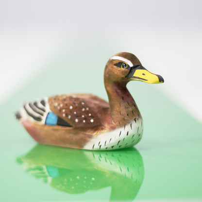 Hand-carved wooden duck ornament showcasing intricate details, perfect for bird lovers and home decor.