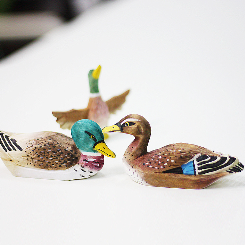 Hand-carved wooden duck ornaments showcasing unique designs and natural wood textures.