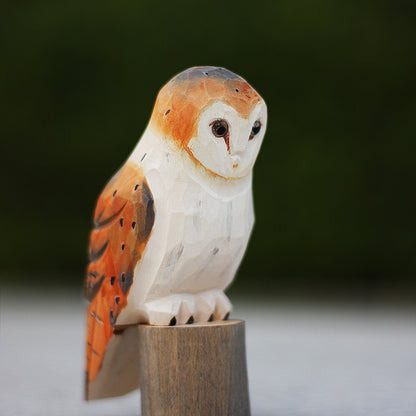 Hand carved long eared owl ornament sits perched on a small wood log.