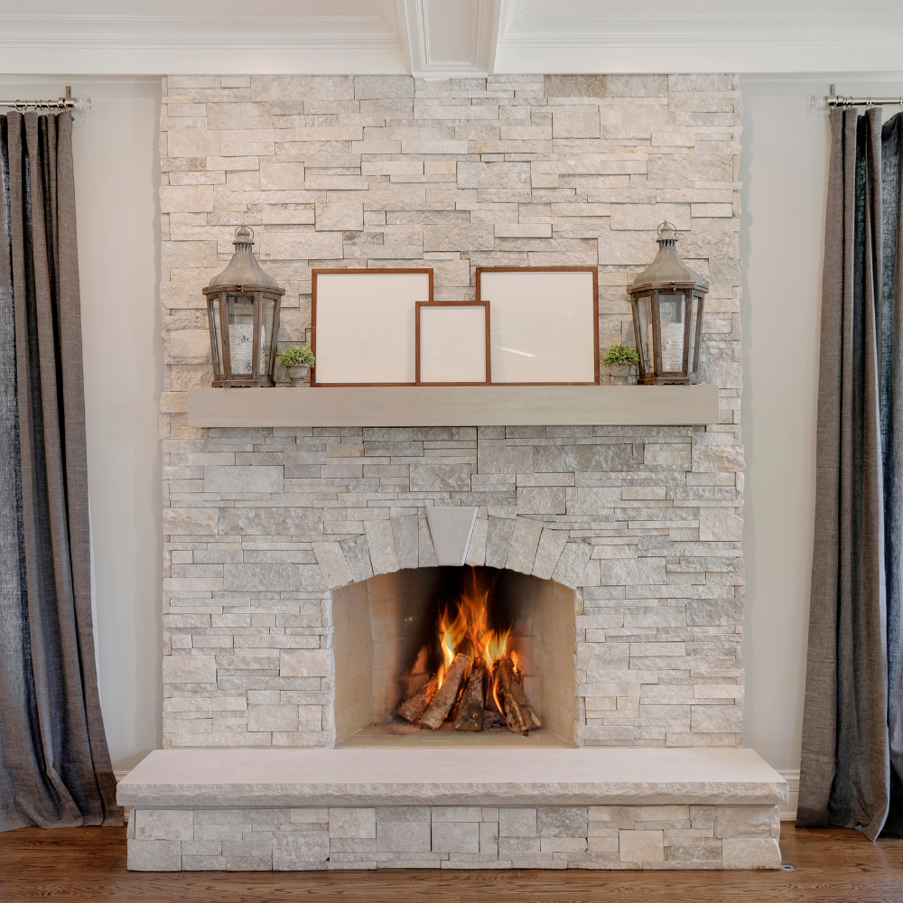 A handmade floating mantel in a light grey stain is featured over a grey fireplace.