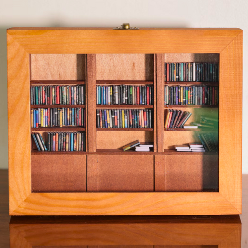 The Anxiety Bookshelf sits on a table with white background. This dimly lit image emphasizes the natural wood tone.