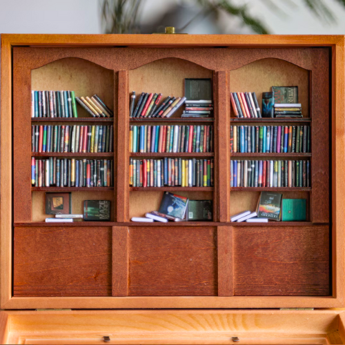 The Original Anxiety Bookshelf mini bookcase sits open showcasing the library of miniature books that come with it.