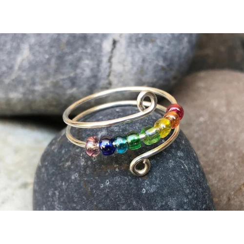 Close up image of a rainbow beaded anxiety ring for fidget, adjustable size.