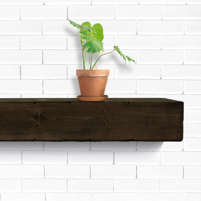 A solid 6x6 cedar dark wood-stained, lightly distressed floating mantel beam sits over a fireplace.