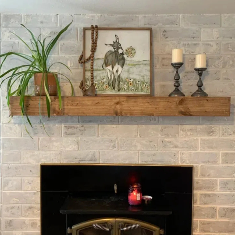 A solid 6x6 cedar wood-stained, lightly distressed floating mantel beam sits over a fireplace.