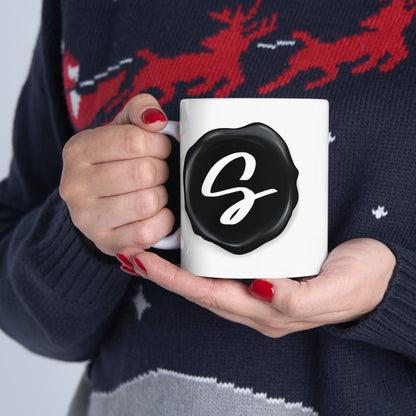 Sydney's Collection black wax seal logo is featured on a coffee mug, held by a model.