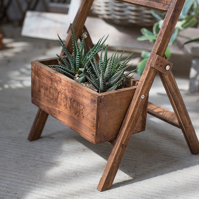 A wooden folding shelf with attached planter and chalkboard to label the plants inside.