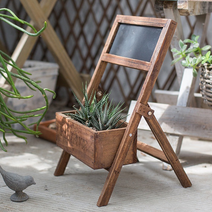 A wooden folding shelf with attached planter and chalkboard to label the plants inside.