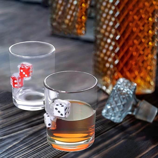 Two hand-blown glass cups with embedded casino dice, showcasing whiskey and a vintage bottle in the background.