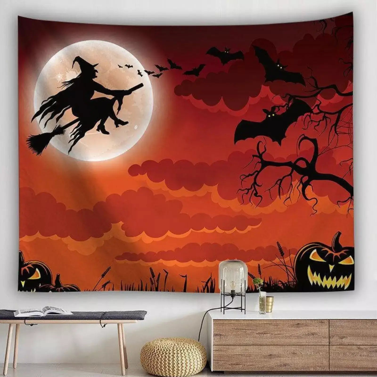 Halloween witch silhouette tapestry with moon, bats, and pumpkins in a spooky orange sky.