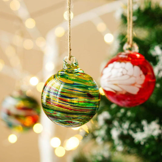 Hand-blown glass sphere ornaments in vibrant colors hanging with holiday lights.