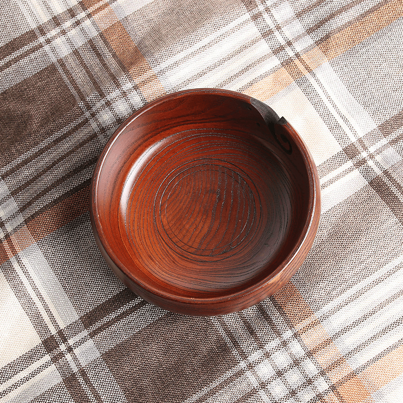 Handmade wooden crochet yarn bowl with smooth finish on plaid background.