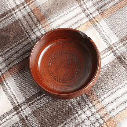 Handmade wooden crochet yarn bowl with smooth finish on plaid background.